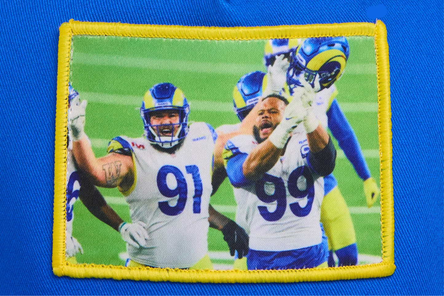 A blue hat featuring a photographic patch of Aaron Donald and Greg Gaines celebrating their Super Bowl win.