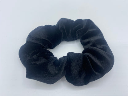 A black velvet scrunchie with a soft, plush texture, featuring a hidden pocket for discreet storage of small items.