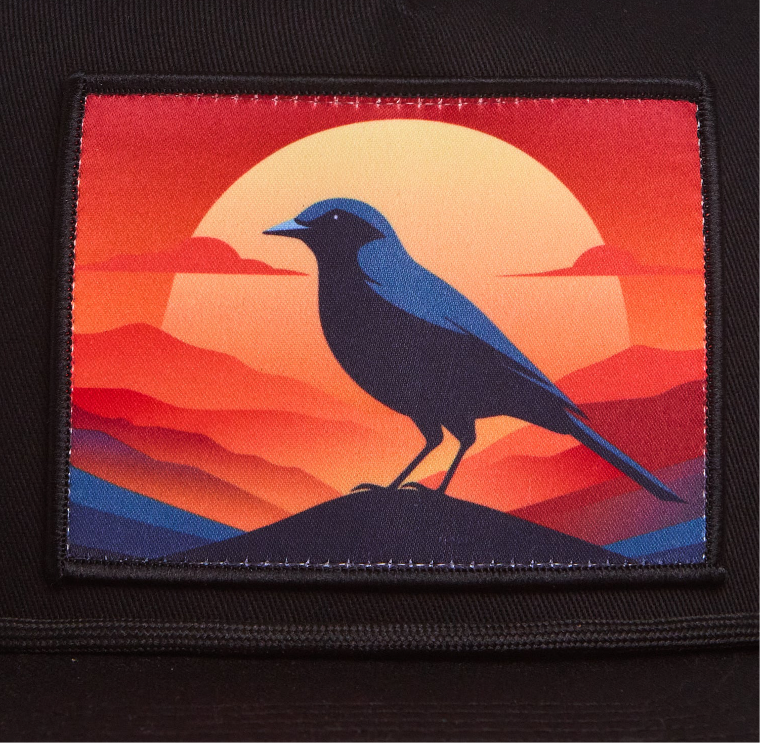 Black hat with a patch of a crow at sunset