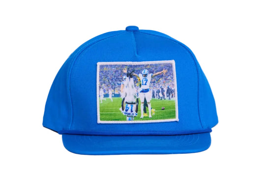 A Honolulu Blue hat featuring the iconic headstand celeration by Amon-Ra St. Brown