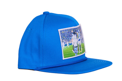 A Honolulu Blue hat featuring the iconic headstand celeration by Amon-Ra St. Brown