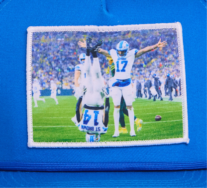 A Honolulu Blue hat featuring the iconic headstand celeration by Amon-Ra St. Brown