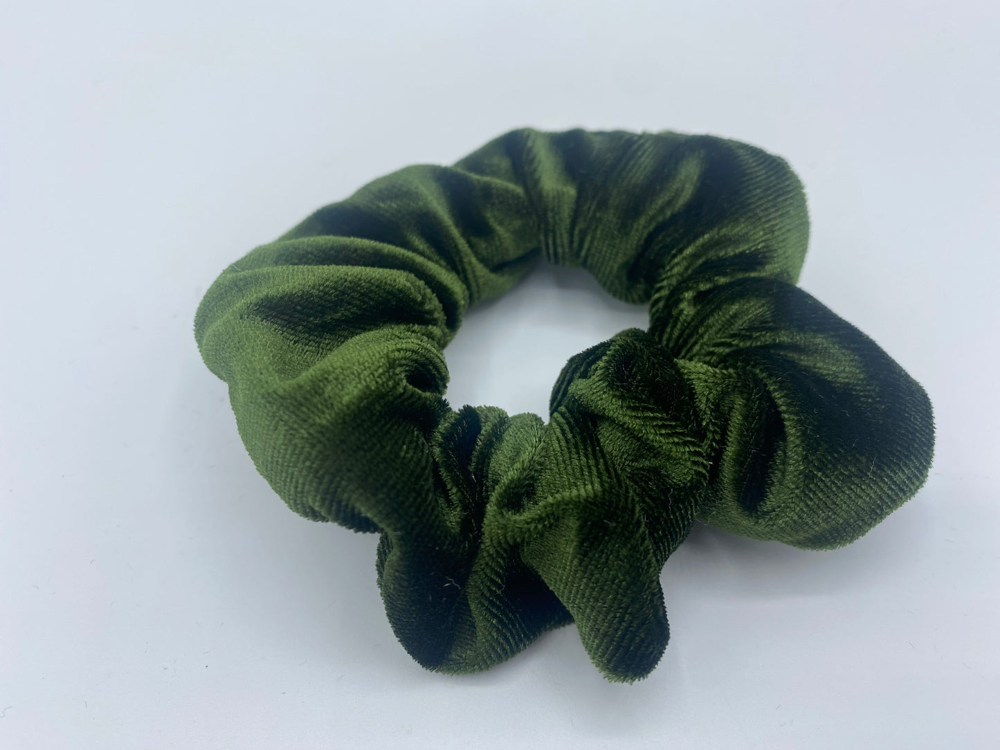 A green velvet scrunchie with a soft, plush texture, featuring a hidden pocket for discreet storage of small items.