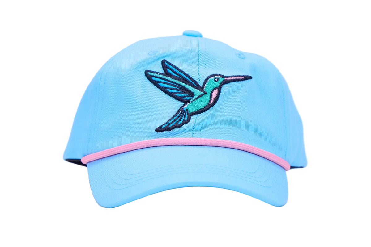 A light blue baseball cap featuring an embroidered hummingbird on the front with a pink accent line along the edge of the brim, set against a plain white background.