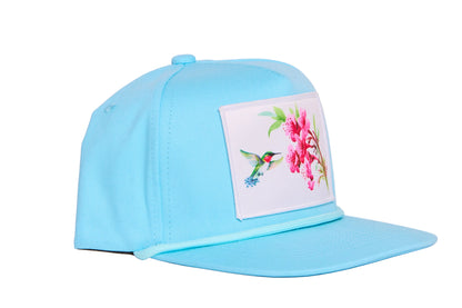 Turquoise blue hat with a patch of a hummingbird and flowers
