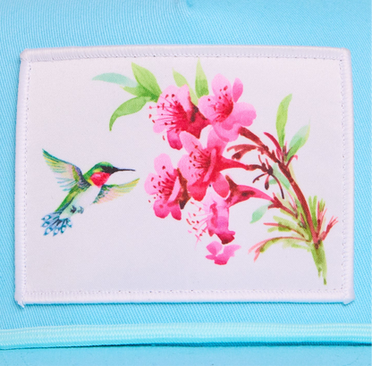 Turquoise blue hat with a patch of a hummingbird and flowers