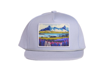 Grey flat-billed hat with a scenic patch featuring mountains and flowers from the southern coast of Iceland