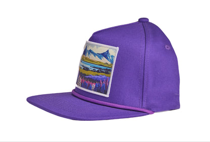Purple flat-billed hat with a scenic patch featuring mountains and flowers from the southern coast of Iceland