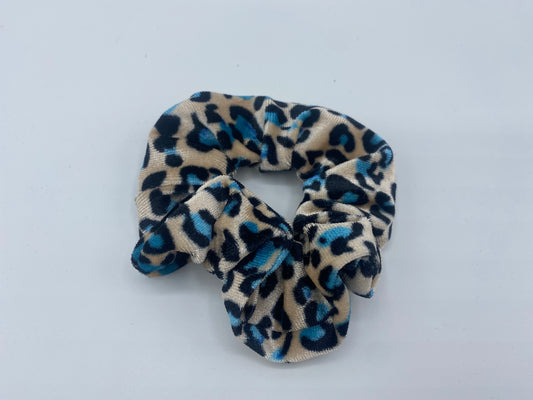 A leopard blue print velvet scrunchie with a soft, plush texture, featuring a hidden pocket for discreet storage of small items.