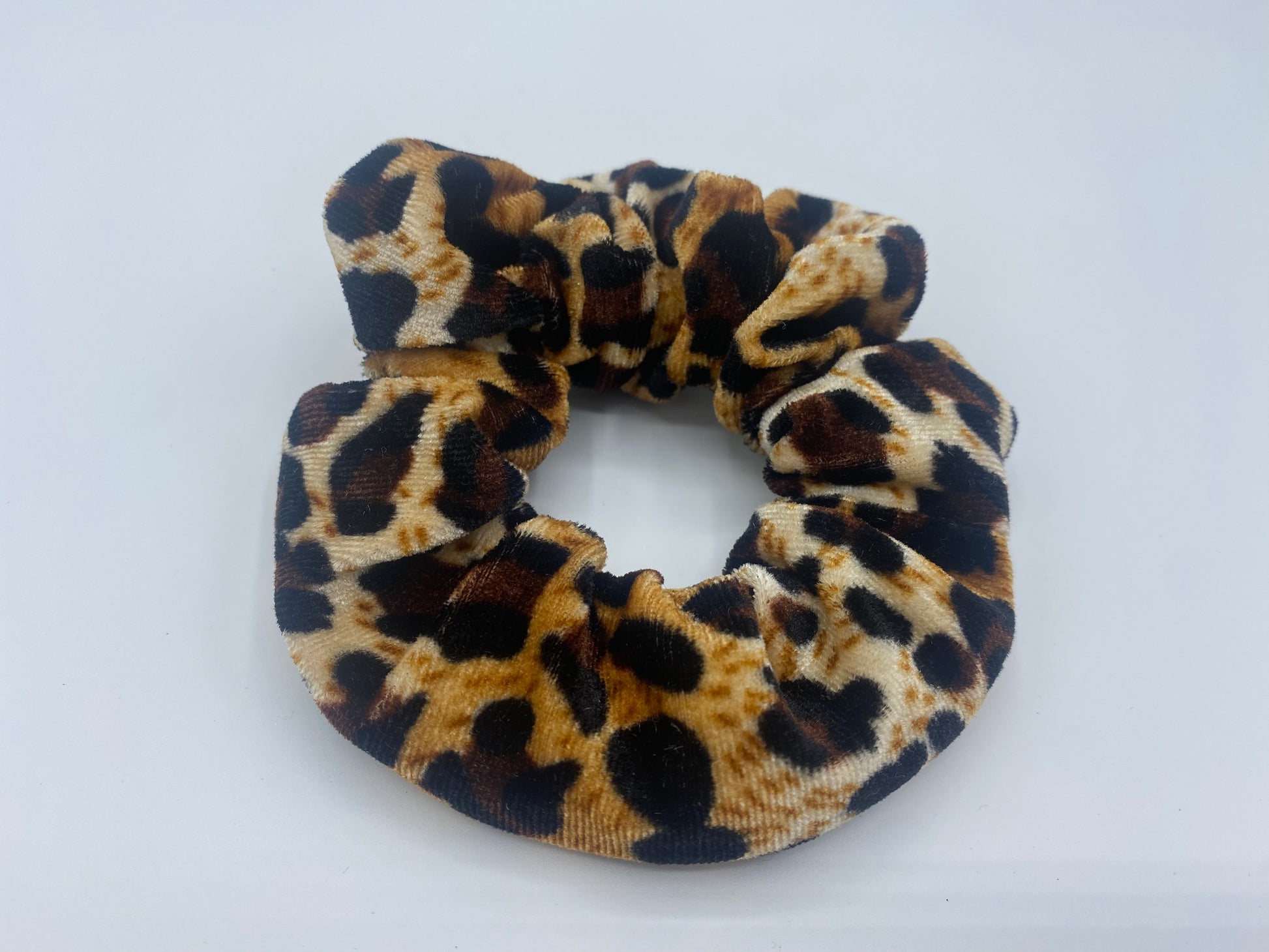 A leopard print velvet scrunchie with a soft, plush texture, featuring a hidden pocket for discreet storage of small items.