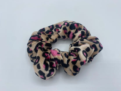 A subtle minimum pink velvet scrunchie with a soft, plush texture, featuring a hidden pocket for discreet storage of small items.