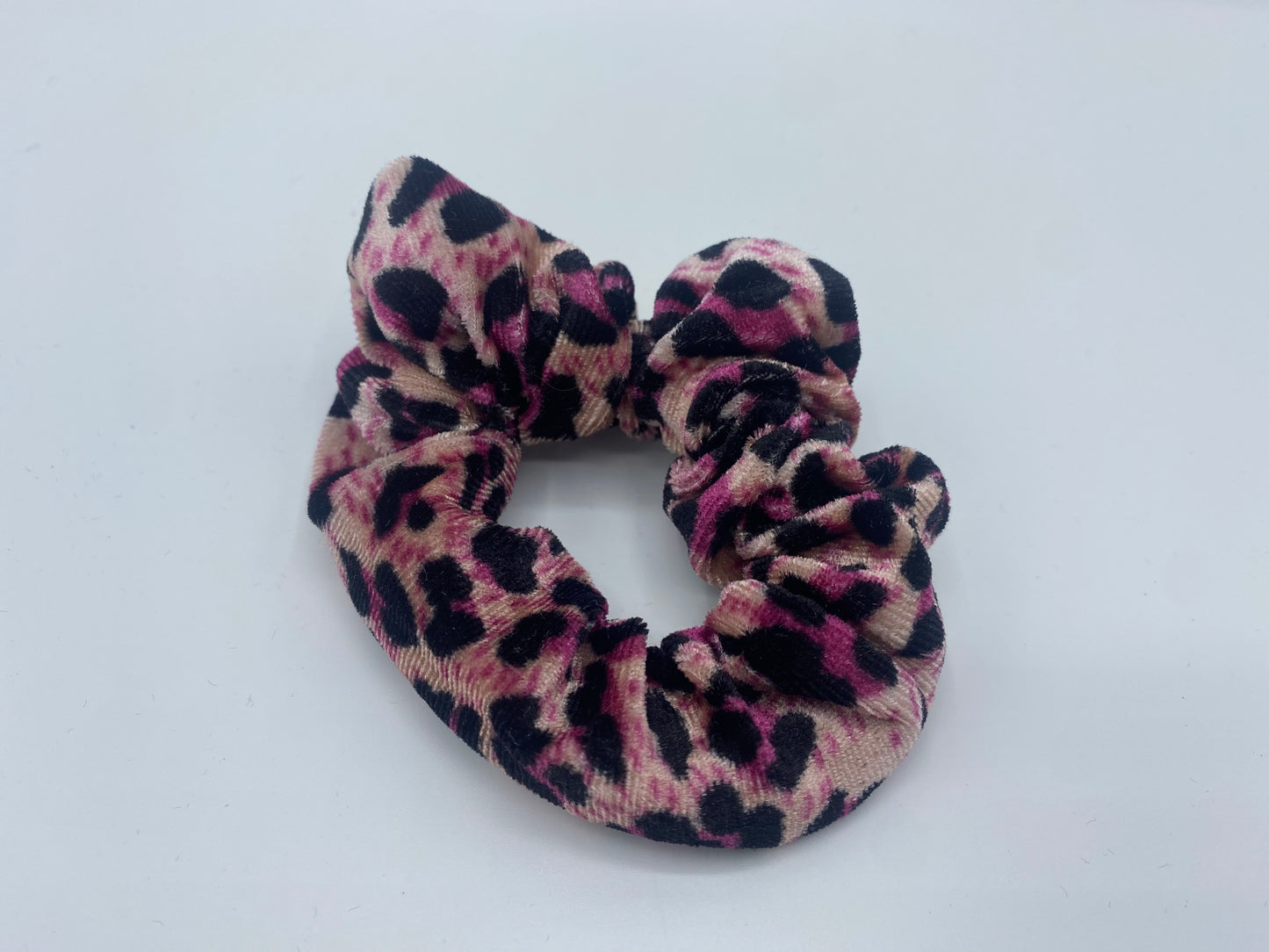 A vibrant maximum pink velvet scrunchie with a soft, plush texture, featuring a hidden pocket for discreet storage of small items.