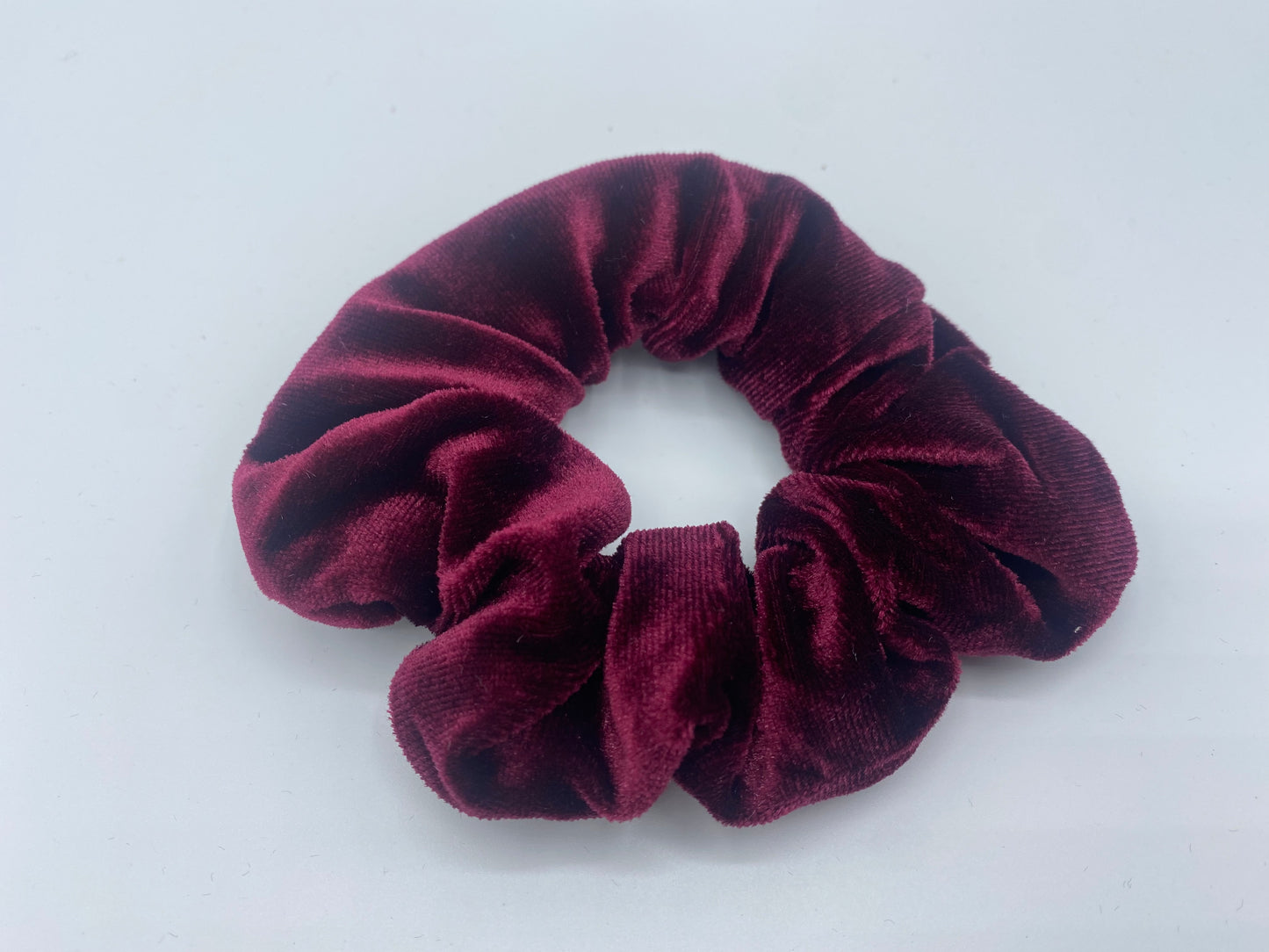 A rich magenta velvet scrunchie with a soft, plush texture, featuring a hidden pocket for discreet storage of small items.