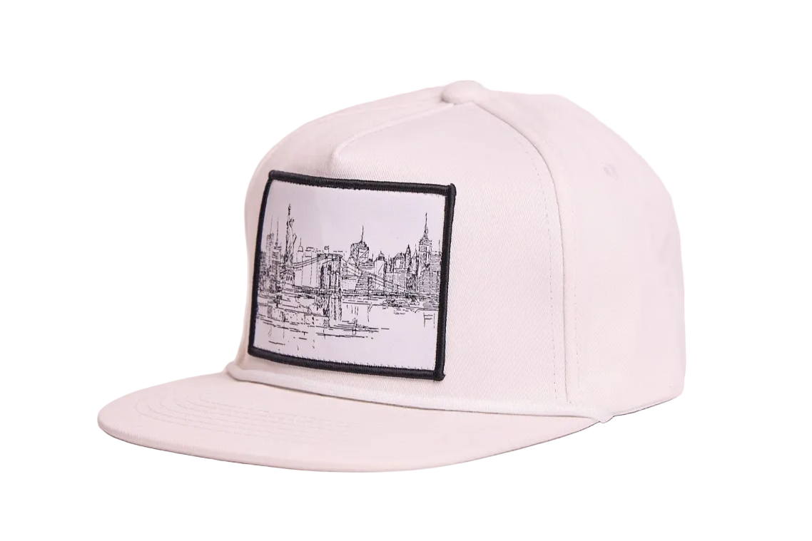 White flat bill hat featuring a patch with a line drawing of the New York City skyline