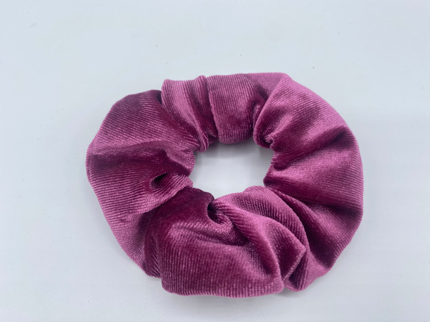 A pink velvet scrunchie with a soft, plush texture, featuring a hidden pocket for discreet storage of small items.