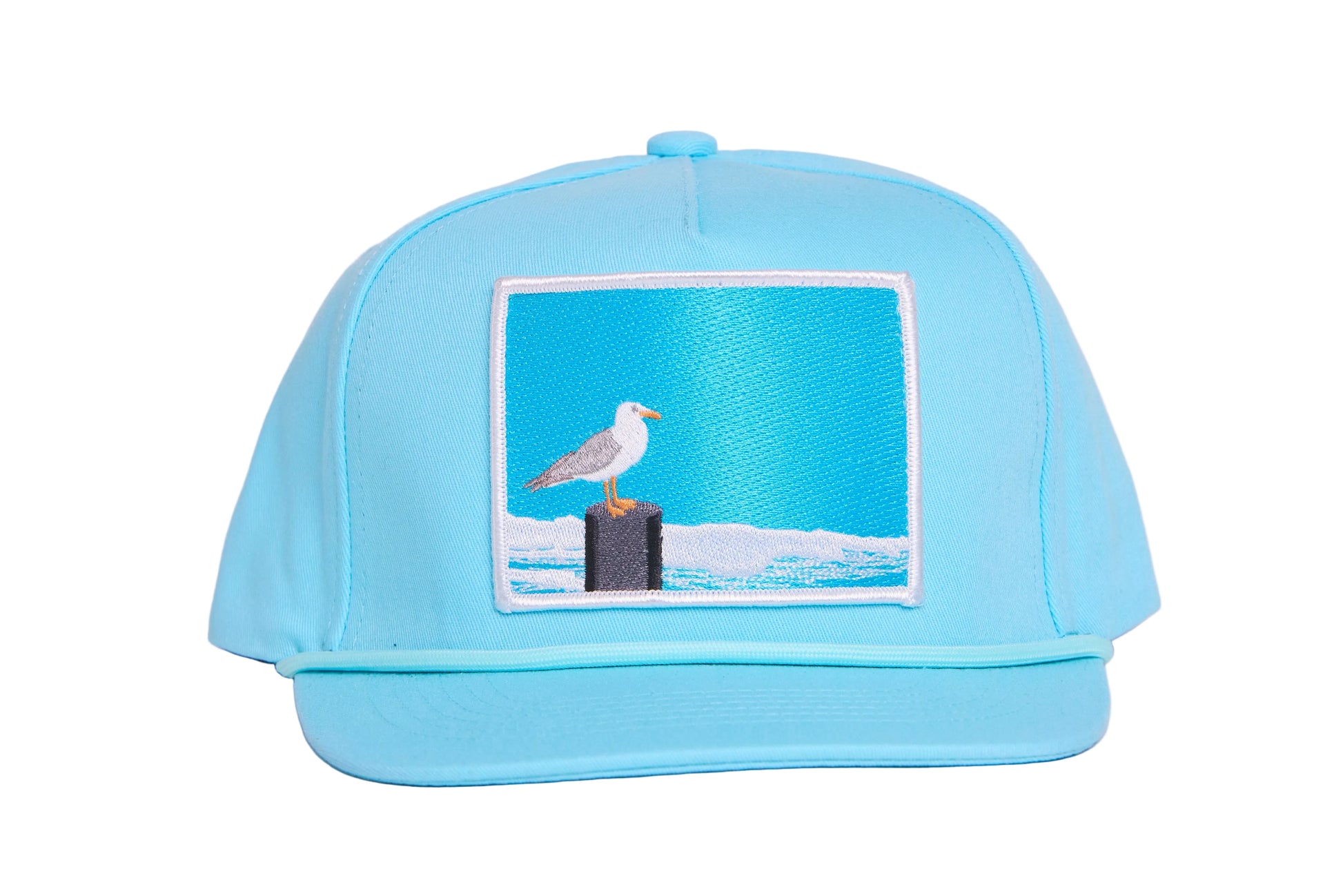 Turquioise ball cap with a light blue embroidered patch featuring a seagull design