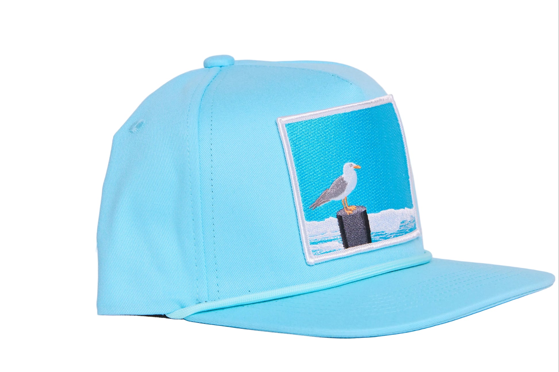 Turquioise ball cap with a light blue embroidered patch featuring a seagull design