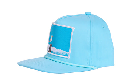 Turquioise ball cap with a light blue embroidered patch featuring a seagull design