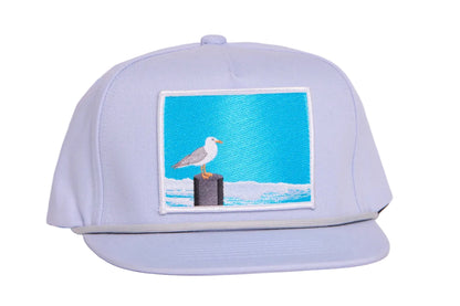 Grey ball cap with blue embroidered patch with a seagull design