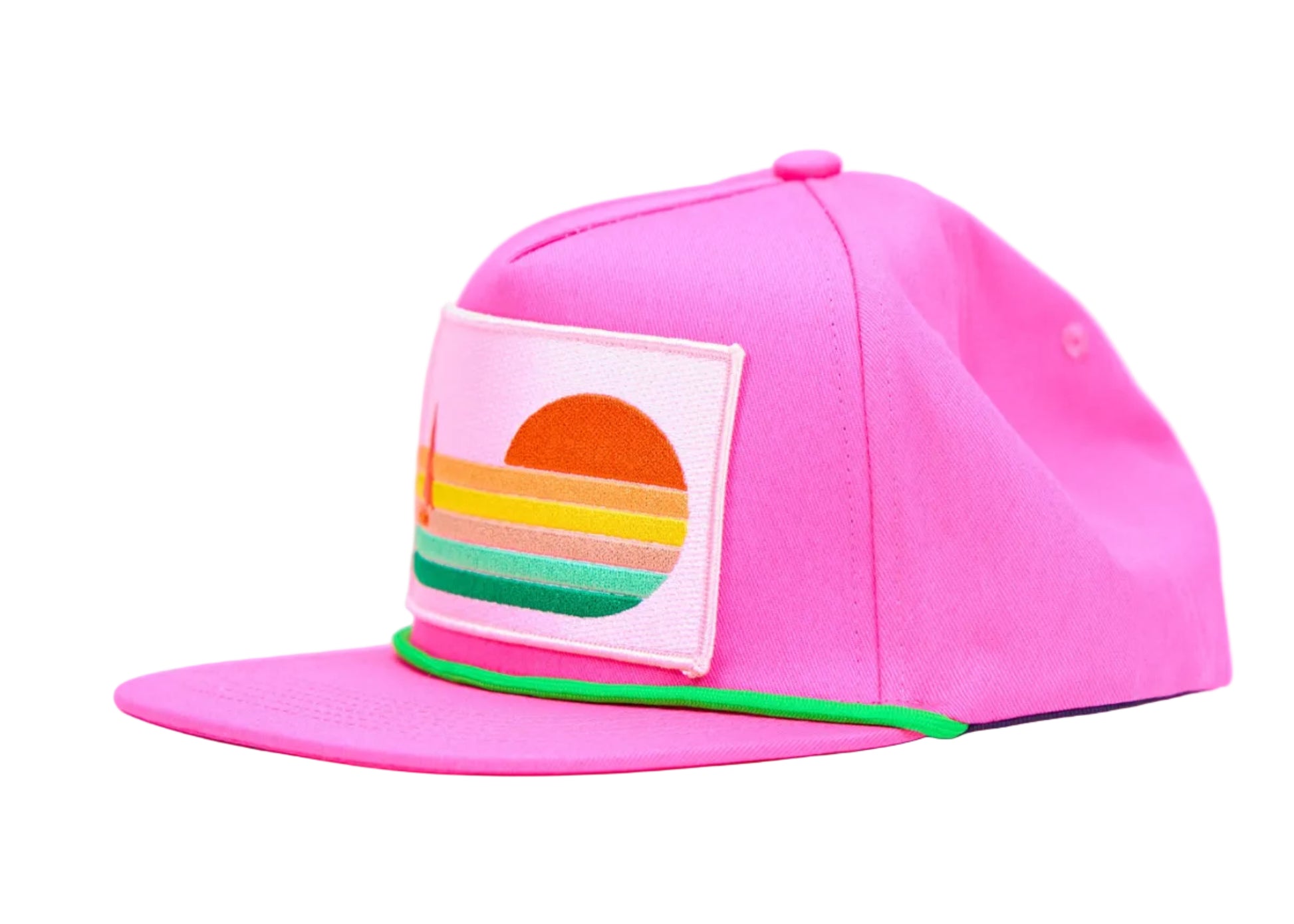 A bright pink snapback cap with a flat brim, featuring a square patch on the front with a retro sunset design in orange, yellow, green, and blue stripes, and a thin green accent line along the edge of the brim.
