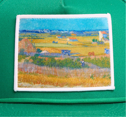 Green flat bill hat with an image of Van Gogh's painting The Harvest