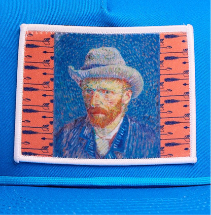 Blue flat-bill hat featuring a patch of Vincent Van Gogh's self portrait in grey felt hat