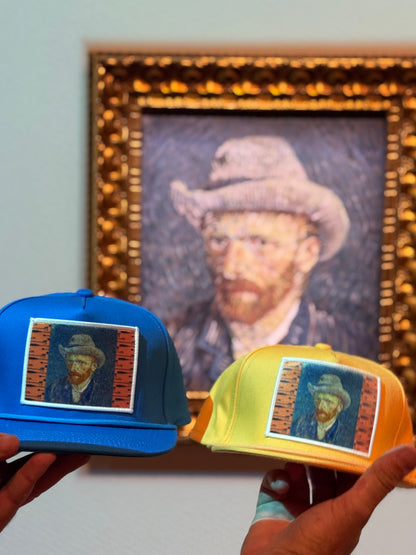 Blue and orange hats featuring a patch of Vincent Van Gogh's self portrait in grey felt hat, taken in front of the actual painting