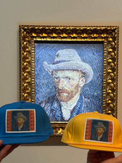 Blue and orange hats featuring a patch of Vincent Van Gogh's self portrait in grey felt hat, taken in front of the actual painting